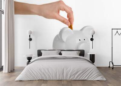 Hand putting coin into piggy bank, isolated on white Wall mural