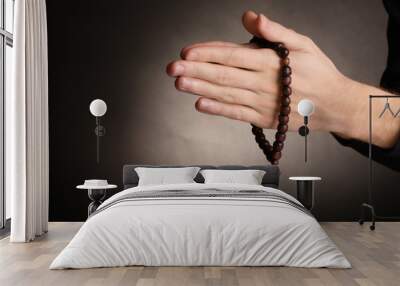 Hands holding wooden rosary on grey background Wall mural