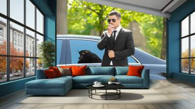 Handsome bodyguard near car outdoors Wall mural