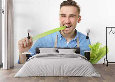 Handsome man eating celery, isolated on white Wall mural