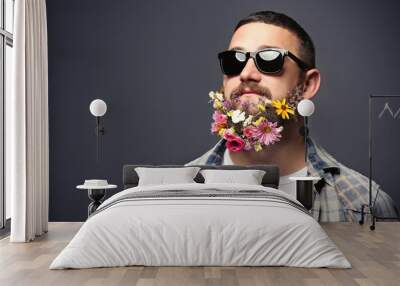 Handsome man in sunglasses with beard of flowers on dark background Wall mural