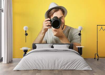 Handsome young photographer on color background Wall mural