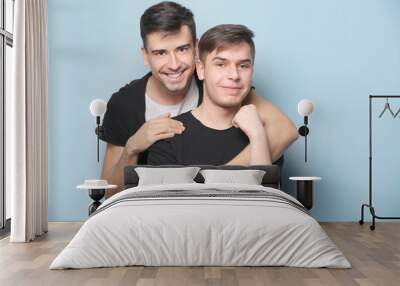 Happy gay couple posing on light background Wall mural