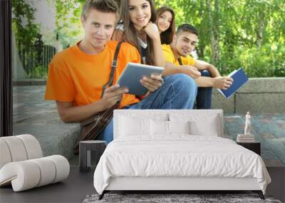 Happy group of young students sitting in park Wall mural