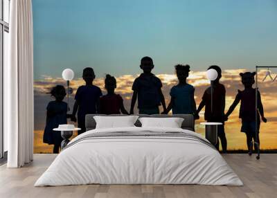 Happy kids silhouettes on sunset background Wall mural