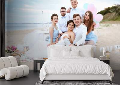 Happy wedding couple with friends on beach Wall mural