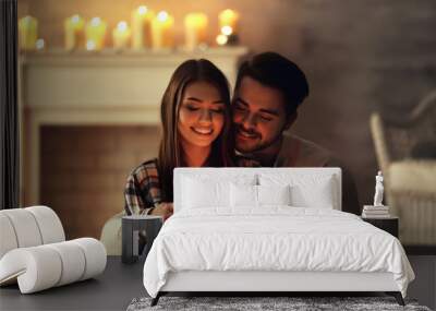 Happy young couple with burning candle at home Wall mural