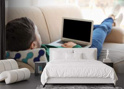 happy young man lying on sofa with laptop Wall mural