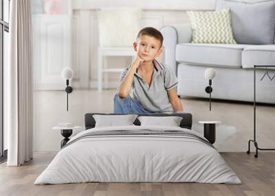 Little boy sitting on carpet, on home interior background Wall mural