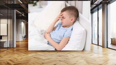 Little boy suffering from headache while lying in bed at home Wall mural