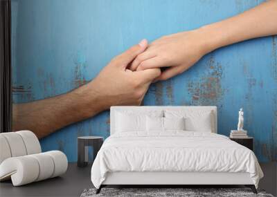 Loving couple holding hands close-up on wooden background Wall mural