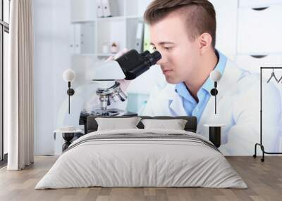 Male scientist using microscope in laboratory Wall mural