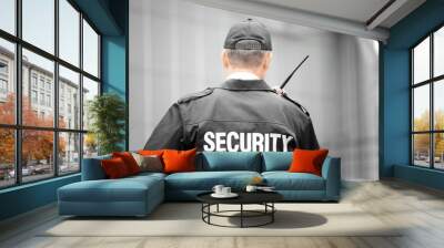 Male security guard using portable radio outdoors Wall mural