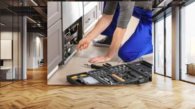 Male technician repairing refrigerator indoors Wall mural