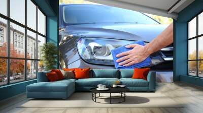 Man cleaning car headlight with rag outdoors Wall mural