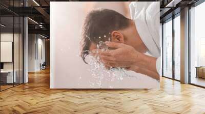 man spraying water on his face after shaving in bathroom Wall mural