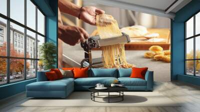 Man using pasta machine to prepare spaghetti, close up view Wall mural