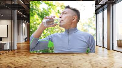 Mature sporty man drinking cool water outdoors Wall mural