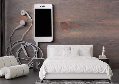 Mobile phone and earphones on wooden background Wall mural