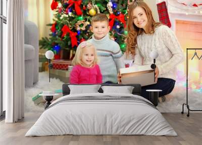 Mother with daughter and son near Christmas tree Wall mural