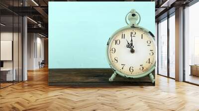 Old alarm clock on wooden table on blue background Wall mural