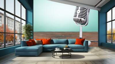 Old metal microphone on wooden table on light blue background Wall mural