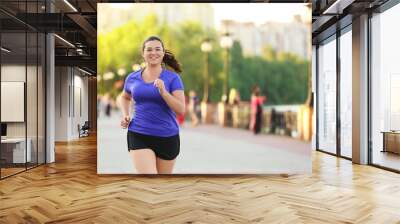 Overweight young woman jogging in the street. Weight loss concept Wall mural