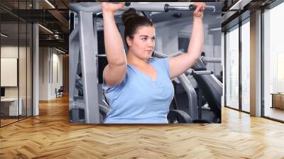 Overweight young woman training in gym Wall mural