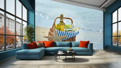 Picnic basket with bottle of wine on sand beach Wall mural