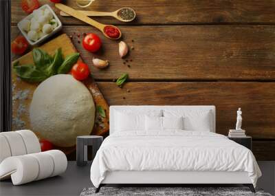 pizza dough with tomatoes, olive oil, green basil and mozzarella on wooden background Wall mural