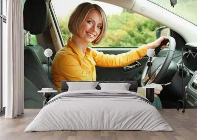 Portrait of young beautiful woman with key sitting in the car Wall mural