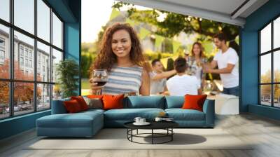 Pretty young woman holding glass of red wine and plate with grilled meat and vegetables Wall mural