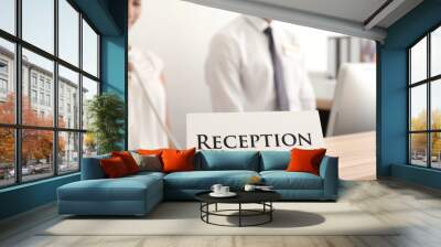 Reception sign and two busy hotel workers on background Wall mural