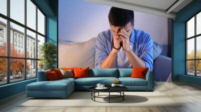 Religious young man with rosary beads praying at home Wall mural