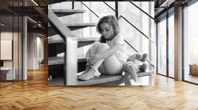 Sad little girl sitting on stairs Wall mural