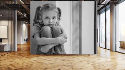 Sad little girl sitting on windowsill, black and white effect Wall mural