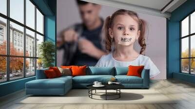 Sad little girl with taped mouth and her father drinking alcohol on background Wall mural