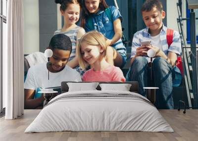 Schoolchildren with mobile phone and tablet computer sitting on school stair-steps Wall mural