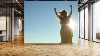 Silhouette of young woman on blue sunny sky background Wall mural