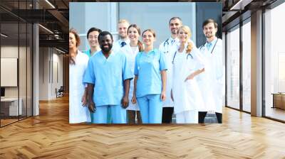 Smiling team of young doctors against hospital entrance Wall mural