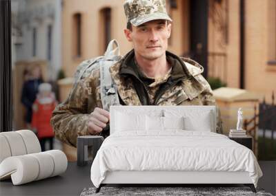 Soldier in camouflage with blurred family on background Wall mural