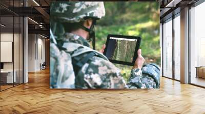 Soldier using map on tablet for orientation at forest Wall mural