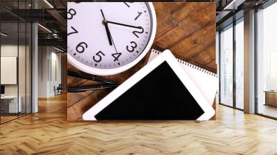 Tablet, cup of coffee, notebook and clock on wooden background Wall mural