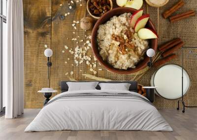 Tasty oatmeal with nuts and apples on wooden table Wall mural