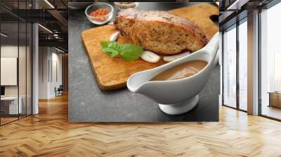 Tasty turkey gravy in sauce boat and cutting board with baked meat on table Wall mural