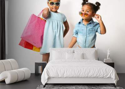 Two cute African girls with shopping bags on white background Wall mural