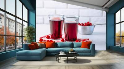 Two glasses with cherry juice on table, on light background Wall mural