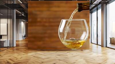 White wine pouring in glass on wooden background Wall mural