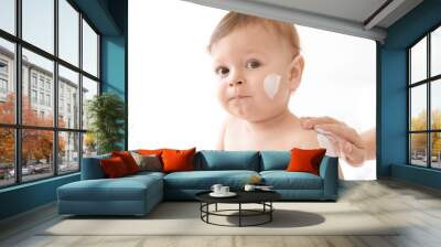 Woman applying body cream on her baby against light background Wall mural