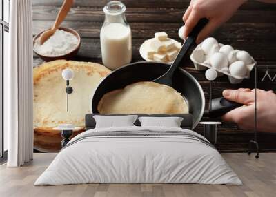 Woman cooking Russian pancakes in kitchen, closeup Wall mural